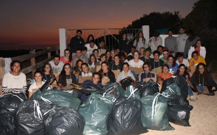 sacos cheios de lixo empilhados no chão com os alunos atrás